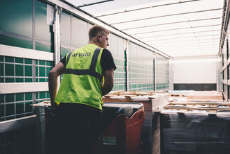A worker in an Arvato high-visibility vest moves pallets into the hold of a truck