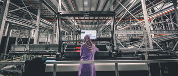 Eine Mitarbeiterin sieht auf den Bildschirm  an ihrem Arbeitsplatz im Lager